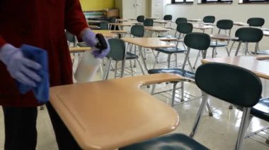 Sprey şişe, eldiven, bez, silme, temizlik ve okul sıralarını dezenfekte eden kadın öğretmenlerin el resimleri..