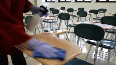 Sprey şişe, eldiven, bez, silme, temizlik ve okul sıralarını dezenfekte eden kadın öğretmenlerin el resimleri..