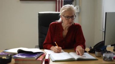 Sınıftaki gülümseyen kadın öğretmenin portresi yukarı bakar ve başparmağını kaldırır. Arka planda Amerikan bayrağı.