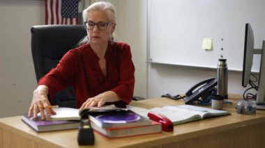 Sınıftaki gülümseyen kadın öğretmenin portresi yukarı bakar ve başparmağını kaldırır. Arka planda Amerikan bayrağı.