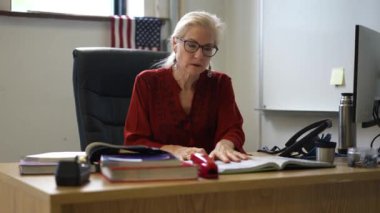 Sınıftaki gülümseyen kadın öğretmenin portresi yukarı bakar ve başparmağını kaldırır. Arka planda Amerikan bayrağı.