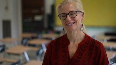 Sınıftaki gülümseyen kadın öğretmenin portresi yukarı bakar ve başparmağını kaldırır. Arka planda Amerikan bayrağı.