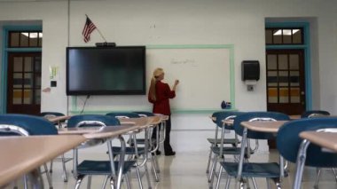 Boş bir sınıfta, interaktif bir beyaz tahta kullanarak geometri öğreten kadın öğretmenin geniş açı görünümü.