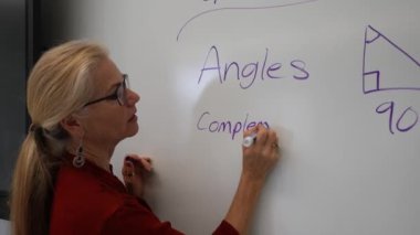 Boş bir sınıfta, interaktif bir beyaz tahta kullanarak geometri öğreten kadın öğretmenin geniş açı görünümü.