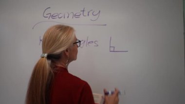 Boş bir sınıfta, interaktif bir beyaz tahta kullanarak geometri öğreten kadın öğretmenin geniş açı görünümü.