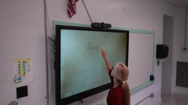 Boş bir sınıfta, interaktif bir beyaz tahta kullanarak geometri öğreten kadın öğretmenin geniş açı görünümü.