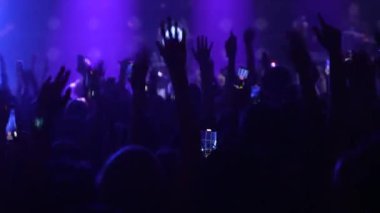 Seyircilerin yavaş çekim yakın çekimleri, ellerinde telefonlar, ellerinde siluetleriyle bando sahnesinde, parlak mavi, flaş ışıkta hareket eden seyirciler. Festivaldeki mutlu insanlar müziğin tadını çıkarıyor