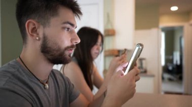Sakallı bir delikanlının telefon kullanarak, kız arkadaşıyla odak uzaklığı dışında mesajlaştığı aşırı yakın plan..