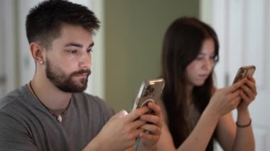 Genç çiftlerin mesajlaşmaları, araştırmaları, yazmaları, telefonları üzerinde çalışmaları, konuşmaları ve evlerindeki bir tezgahta mesajlaşmaları....