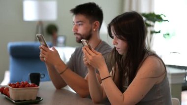 Genç çiftin telefonlarıyla ilgili bilgi paylaşıp evlerindeki bir gişede konuşup mesajlaşmaları..