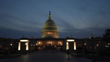 Kamyon görüntüsü solda, gece Washington DC 'de mavi mor gökyüzüne karşı sallanan ışık ve bayraklarla Birleşik Devletler Kongre Binası' nı gösteriyor..