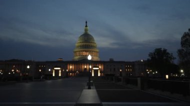 Kamyon görüntüsü solda, gece Washington DC 'de mavi mor gökyüzüne karşı sallanan ışık ve bayraklarla Birleşik Devletler Kongre Binası' nı gösteriyor..