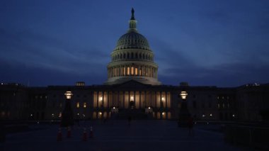 Kamyon görüntüsü solda, gece Washington DC 'de mavi mor gökyüzüne karşı sallanan ışık ve bayraklarla Birleşik Devletler Kongre Binası' nı gösteriyor..
