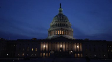 Kamyon görüntüsü solda, gece Washington DC 'de mavi mor gökyüzüne karşı sallanan ışık ve bayraklarla Birleşik Devletler Kongre Binası' nı gösteriyor..