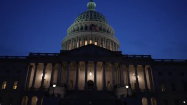 Kamyon görüntüsü solda, gece Washington DC 'de mavi mor gökyüzüne karşı sallanan ışık ve bayraklarla Birleşik Devletler Kongre Binası' nı gösteriyor..