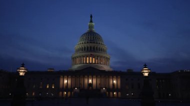 Kamyon görüntüsü solda, gece Washington DC 'de mavi mor gökyüzüne karşı sallanan ışık ve bayraklarla Birleşik Devletler Kongre Binası' nı gösteriyor..