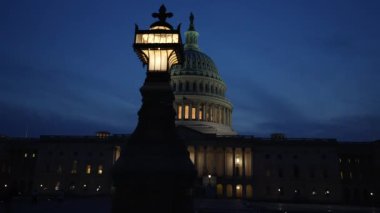 Kamyon görüntüsü solda, gece Washington DC 'de mavi mor gökyüzüne karşı sallanan ışık ve bayraklarla Birleşik Devletler Kongre Binası' nı gösteriyor..