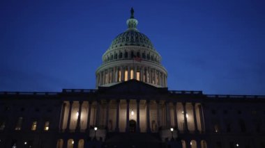 Kamyon görüntüsü solda, gece Washington DC 'de mavi mor gökyüzüne karşı sallanan ışık ve bayraklarla Birleşik Devletler Kongre Binası' nı gösteriyor..