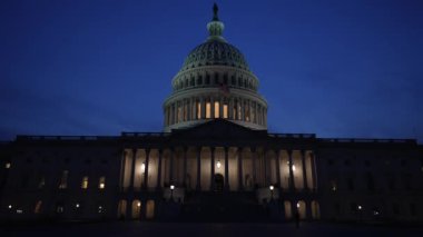 Kamyon görüntüsü solda, gece Washington DC 'de mavi mor gökyüzüne karşı sallanan ışık ve bayraklarla Birleşik Devletler Kongre Binası' nı gösteriyor..