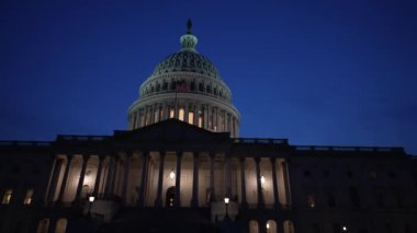 Kamyon görüntüsü solda, gece Washington DC 'de mavi mor gökyüzüne karşı sallanan ışık ve bayraklarla Birleşik Devletler Kongre Binası' nı gösteriyor..