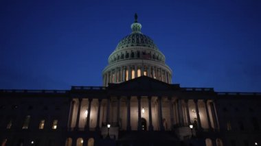 Gece Washington DC 'de karanlık bir gökyüzüne karşı sallanan ışık ve bayraklarla Birleşik Devletler Kongre Binası' nı yavaş çekimde gösteriyor..