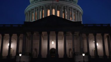 Ağır çekim yakın çekim kamera, gece Washington DC 'de bayrakları sallanan ve mimarisinde ışıklar olan Amerikan Kongre Binası' nı gözler önüne seriyor..