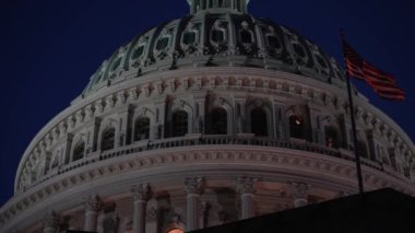 Gece gökyüzüne karşı rüzgarda dalgalanan bayrağıyla ABD Capitol Kubbesi 'ne çok yakın..
