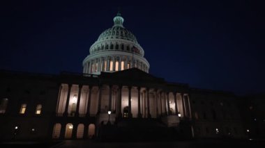 Washington DC 'de bayrakları dalgalanan ve mimarisinde ışıklar olan Amerikan Kongre Binası' nın durağan gece manzarası..