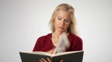 Mutlu, güzel, yaşlı, sarışın kadın portresi. 50 'li yaşlarda. Süveter giyip kitap okuyor.
