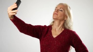 Orta yaşlı kadın akıllı telefonuyla selfie çekiyor. Görüntülü sohbet konferansında telefonla konuşan portre.