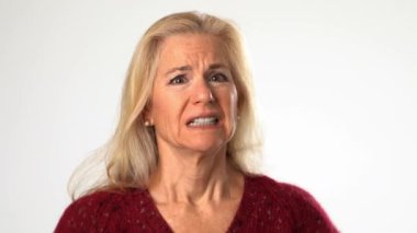 Mutsuz, olgun, yaşlı bir kadının gürültüden dolayı elleriyle kulaklarını kapatması stüdyoda beyaz arka planda izole edilmiş ayakta duran bir model.