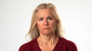 Sinirli, sinirli, sinirli, olgun, sarı saçlı, beyaz arka planda yalnız bir kadının yakın plan portresi..