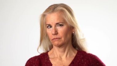 Kendine güvenen yaşlı, gri saçlı, 50 'li yaşlarda bir kadının yakın plan portresi. Parmağıyla işaret ediyor. Beyaz arka plan stüdyosunda izole edilmiş bir jest gibi.