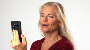 Sarışın, olgun bir kadın. Beyaz arka planda görüntülü konuşma yapıyor. Gülümseyen ve mutlu bir konsept olan arkadaş, aile işadamı.