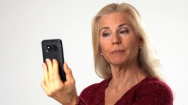 Sarışın, olgun bir kadın. Beyaz arka planda görüntülü konuşma yapıyor. Gülümseyen ve mutlu iletişim konsepti iş adamı iş konuşur.