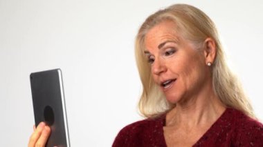 Tablet bilgisayarlı mutlu olgun bir kadının beyaz arka planda görüntülü sohbet etmesi. İnsanlar ve iletişim konsepti