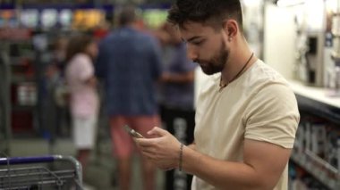 Hırdavatçı deposundaki eşyaları aramak için telefon kullanan adama yakın çekim..
