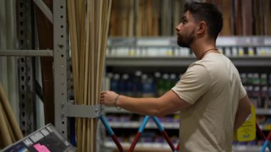 Hırdavatçıda ev yenileme projesi için kereste seçen ve karşılaştıran bir adam.