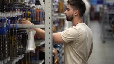 Hırdavatçı dükkanındaki elektrikli teçhizat için matkap ucu arayan bir adam..