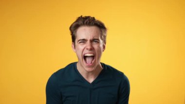 Kızgın sinirli genç adamın portresi. 20 'li yaşlarda, sarı arka planda izole edilmiş..