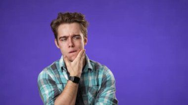 Portrait of thinking, smart puzzled pensive young hipster man 20s looks around thinks comes up with ideas raised finger thumbs up isolated on purple background studio portrait