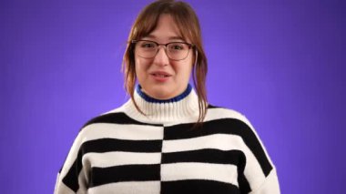 Mor arka plan stüdyosunda izole edilmiş 20 'li yaşlarda güzel esmer bir kadının portresi. Gülümsemenin ve mutlu olmanın imkânı yok..