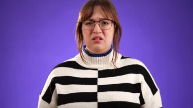 Kahverengi saçlı, ağlamak üzere olan gözlüklü ve süveterli, mor arka planda, fotokopi alanı olan mutsuz bir kadının portresi..