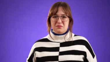 20 'li yaşlardaki güzel esmer kadın dün gece partiden sonra yeterince uyuyamadı ve sabahları zar zor esneyerek uyandı. Stüdyoda mor arkaplanda izole edilmiş portre.