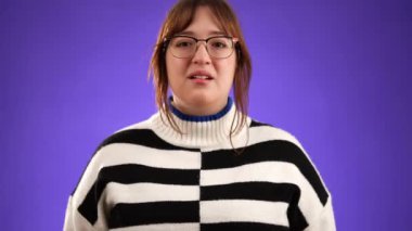 Dua ederken el ele tutuşup yalvarırken parmaklarını çapraz yap güzel esmer kadın 20 'li yaşlarda mor arka plan stüdyosunda izole edilmiş ve fotokopi alanı yavaş çekimde.