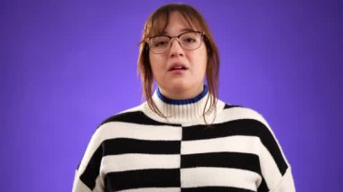 20 'li yaşlarda mutlu, mutlu bir kadının portresi. O kadar tatlıydı ki. Mor arka plandaki stüdyo portresi üzerinde izole edilmiş sandığa uzandı. Halk yaşam tarzı konsepti