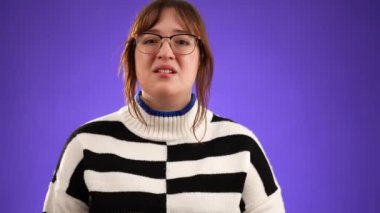 Dua ederken el ele tutuşup yalvarırken parmaklarını çapraz yap güzel esmer kadın 20 'li yaşlarda mor arka plan stüdyosunda izole edilmiş ve fotokopi alanı yavaş çekimde.