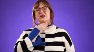 Öksürük ve boğaz ağrısı olan 20 'li yaşlardaki genç bir kadının portresi stüdyoda mor arka planda, fotokopi aletiyle izole edilmiş.