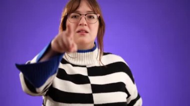 Mutlu, 20 'li yaşlardaki genç bir kadının portresi elinde telefonla beni ara diyor, stüdyoda mor arka planda izole edilmiş.