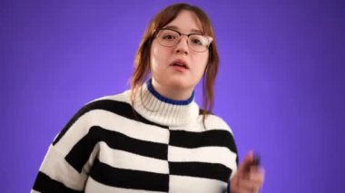 Mutlu, 20 'li yaşlardaki genç bir kadının portresi elinde telefonla beni ara diyor, stüdyoda mor arka planda izole edilmiş.